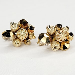 May include: A pair of gold tone clip-on earrings with a cluster of faceted glass and gold tone beads.