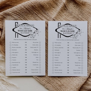 May include: Two black and white printable game cards with the text "Welcome to Michelle's Would She Rather?" and a list of questions with "OR" between each choice. The cards feature a black and white illustration of a Las Vegas sign with dice.