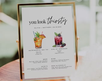 May include: A gold-framed sign with the text "you look thirsty" and the date "06.18.2025". The sign lists drink options for a wedding, including "Matrimonial Mai Tai" and "Sips of Serenade", with illustrations of the cocktails.
