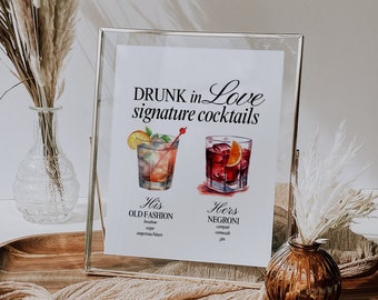 May include: A framed sign with the text "DRUNK in Love signature cocktails" and illustrations of two cocktails. The text below the illustrations reads "His OLD FASHION bourbon, sugar, angostura bitters" and "Hers NEGRONI campari, sweet vermouth, gin".