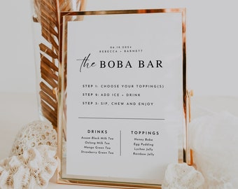 May include: A gold-framed sign with the text "the BOBA BAR" and instructions for making a boba drink. The sign lists the drinks available: Assam Black Milk Tea, Oolong Milk Tea, Mango Green Tea, and Strawberry Green Tea. The toppings available are: Honey Bobo, Egg Pudding, Lychee Jelly, and Rainbow Jelly.
