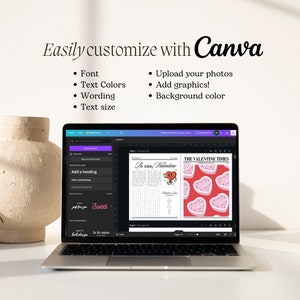 May include: A laptop screen displaying a Canva design template for a Valentine's Day newspaper. The template features a red heart with the text "Be mine, Valentine" and a crossword puzzle. The text "The Valentine Times" is at the top of the page. The laptop is on a white desk with a vase of flowers in the background.