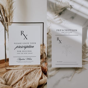 May include: A white sign with a black Rx symbol and the text "PLEASE LEAVE YOUR prescription FOR SUCCESS FOR THE NEW GRAD!"  The sign is in a clear frame and is sitting on a brown surface.  The text "Angelina Wilson UNIVERSITY OF NEVADA LAS VEGAS BACHELOR OF SCIENCE IN NURSING" is at the bottom of the sign.