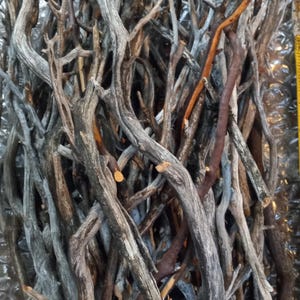 Pode incluir: Um monte de galhos de madeira flutuante cinzentos e marrons, perfeitos para artesanato ou decoração.