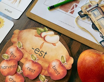 May include: Educational materials for children, including flashcards with illustrations of wheat and a beet, and apple-shaped cards with words like "test" and "harvest". A drawing activity sheet and a green pencil are also visible.