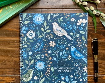 Puede incluir: Una agenda escolar de espiral con una cubierta azul oscuro que presenta un patrón de pájaros, flores y follaje en azul claro y blanco. El texto "WILLOW GROVE HOMESCHOOL PLANNER" está impreso en blanco en la portada de la agenda.