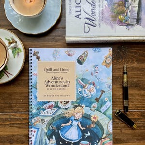 May include: A spiral-bound notebook titled Quill and Lines Alice's Adventures in Wonderland by Lewis Carroll by Books and Willows, featuring a colorful illustration of Alice in a blue dress, teacups, and playing cards on the cover.