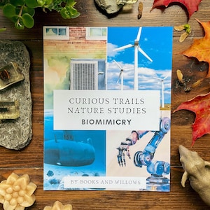 Puede incluir: Una portada de libro con una ilustración de acuarela de un submarino, turbinas eólicas y un brazo robótico. El título es "Curious Trails Nature Studies Biomimicry" y el libro es de "Books and Willows".