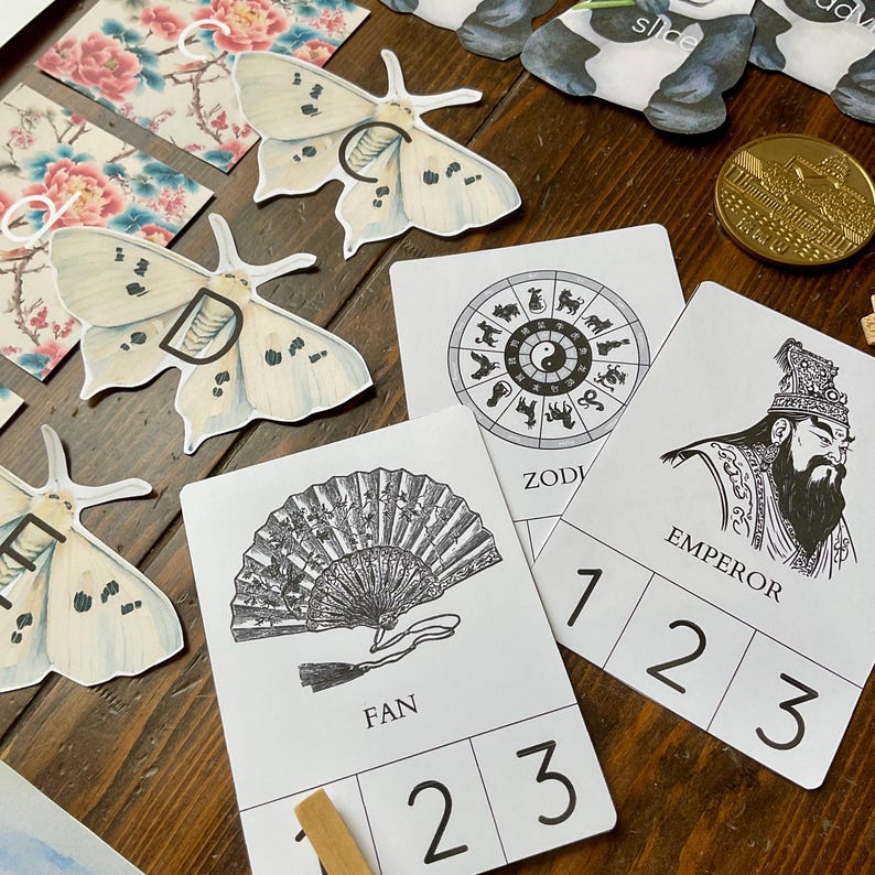 May include: A set of four cards with Chinese-inspired illustrations and numbers 1, 2, and 3 printed on each card. The illustrations include a fan, a zodiac wheel, an emperor, and a moth.