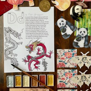 May include: A printable worksheet with a large letter D and the text "is for dragon". The worksheet includes a black and white illustration of a dragon, a red and gold dragon, and a description of the Chinese dragon. The worksheet is surrounded by various Chinese-themed decorations, including a panda, a butterfly, and a watercolor paint set.