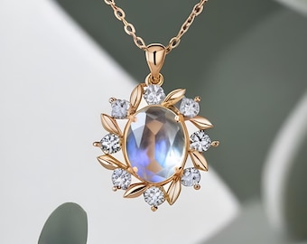 May include: A gold necklace with a pendant featuring a large oval moonstone surrounded by smaller clear stones and gold leaf designs.