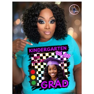 Könnte beinhalten: Ein hellblaues T-Shirt mit dem Text "KINDERGARTEN THE 1st LAP GRAD". Das Shirt zeigt eine Grafik eines Kindes mit Abschlusskappe, einer Zielflagge und einer Ampel.