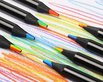 May include: Set of rainbow colored pencils with black barrels. The pencils are arranged in a staggered pattern on a white surface.