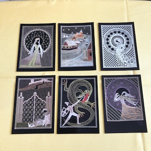 May include: Six embroidered artworks on black fabric. The images show medieval scenes, including a woman in a gown, a snowy village, a serpent, a knight battling a dragon, and a woman with flowing hair. The embroidery is detailed.