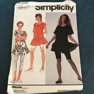 May include: A vintage Simplicity sewing pattern, size A (PT-XL), with illustrations of three outfits. The pattern includes instructions for a dress, top, and leggings. The cover features the Simplicity logo and the Overlock/Serger logo.