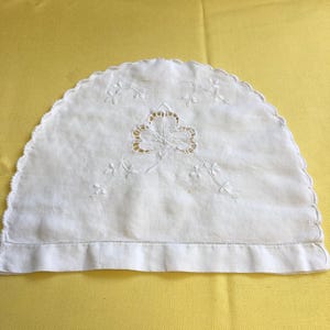 May include: White crocheted tea cosy with an embroidered shamrock design.