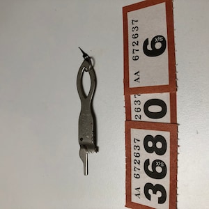 May include: A silver-colored key with a loop at the top and a serrated edge. The key is labeled with the text "AA 672637 6".