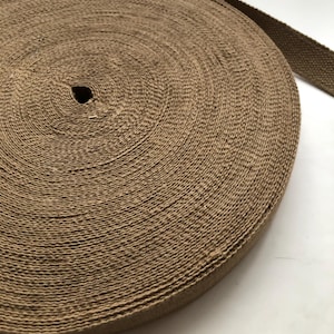 May include: A roll of brown cotton webbing, a type of strong, woven fabric often used for straps, belts, and other applications.