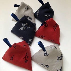 Peut inclure: Cinq poids en tissu triangulaires avec un motif floral et des poignées en ruban bleu. Les poids sont en rouge, bleu et beige.