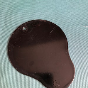May include: A black metal dental tool with a rounded, irregular shape and a small hole at the top. The tool has a number "8459" etched on the surface.