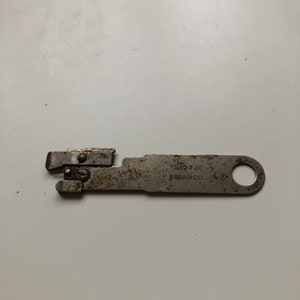 May include: A silver can opener with a hole in the handle. The text "121632" and "SIMANCO" are printed on the opener.