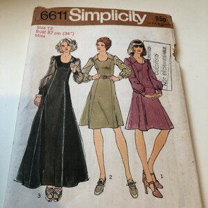 May include: Vintage Simplicity sewing pattern 6611, size 12, with illustrations of three dresses. The pattern includes bust measurements of 87 cm (34 inches). The cover is off-white with text and illustrations in black, brown, and various colours.