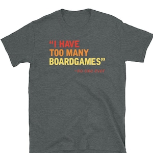 May include: Dark heather grey t-shirt with a humorous quote in a retro font: "I have too many boardgames" - no one ever.