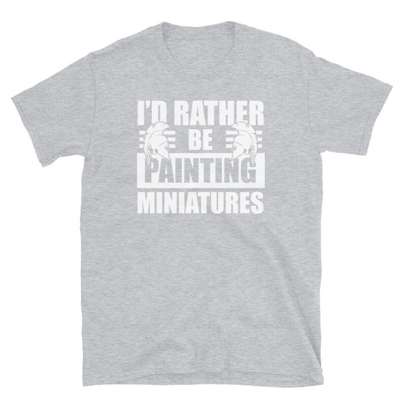 May include: Gray short-sleeved t-shirt with white text that reads "I'd rather be painting miniatures". The text is framed by two white helmet graphics.
