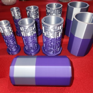 May include: A set of seven silver and purple cylindrical containers with a geometric pattern. The containers are made of plastic and have a smooth finish.