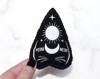 May include: Black felt triangle with a white sun, moon, and stars design. The text "MEOW" appears twice on the triangle.