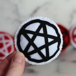 White circle catnip cat toy with black pentacle, pentagram detail on the front.