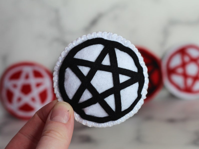 White circle catnip cat toy with black pentacle, pentagram detail on the front.