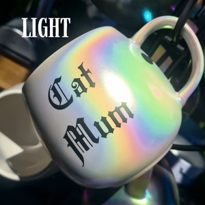 May include: A white iridescent ceramic mug with a black gothic font design that reads "Eat Mum".