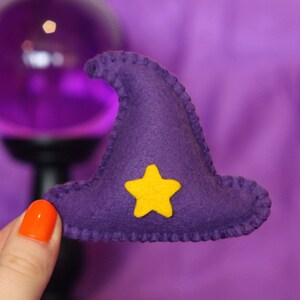 Pu&ograve; includere: Un cappello da strega in feltro viola con una stella gialla in feltro sul davanti. Il cappello &egrave; fatto a mano e ha un bordo cucito.