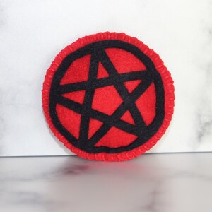 Red circle catnip cat toy with black pentacle, pentagram detail on the front.