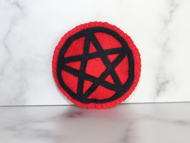 Red circle catnip cat toy with black pentacle, pentagram detail on the front.