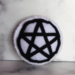 White circle catnip cat toy with black pentacle, pentagram detail on the front.