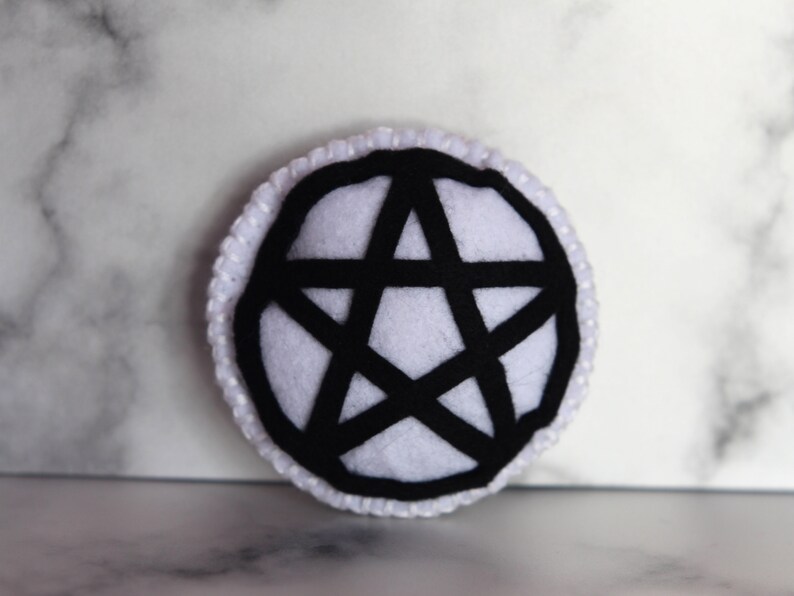 White circle catnip cat toy with black pentacle, pentagram detail on the front.