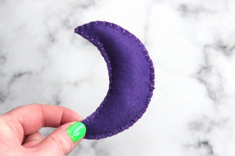 May include: A purple felt crescent moon with a stitched edge.