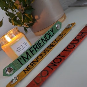 May include: Three colorful wristbands with different messages: "I'm Friendly", "Nervous Rescue", and "Do Not Touch".