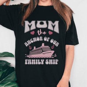 Puede incluir: Camiseta negra con un gráfico rosa que dice "Mom the anchor of our family ship" con un corazón rosa y un crucero rosa.
