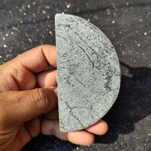 May include: A half-circle shaped piece of green and grey stone with a rough, textured surface.