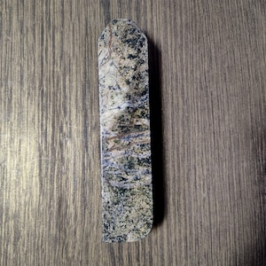 Può includere: Una maniglia per porta rettangolare lunga e stretta realizzata in marmo verde e marrone con un motivo screziato.