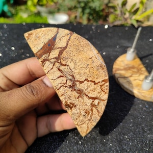 Puede incluir: Dos pomos de armario de piedra de forma semicircular, de color marrón y beige, con un patrón de mármol y herrajes de metal plateado.