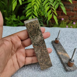 May include: Two brown stone drawer pulls with silver metal hardware. The pulls are rectangular and have a rough, textured surface.