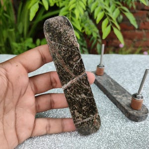 May include: Two brown and black marble cabinet knobs with silver screws and a copper base.