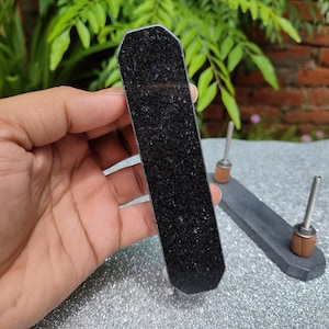 May include: A black and silver drawer pull with a textured black surface. The pull is made of metal and has a rectangular shape.