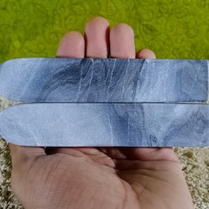 Könnte beinhalten: Zwei graue rechteckige Siegelwachs-Stempel mit Marmorierung.