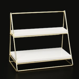 May include: A gold metal two-tiered shelf with white shelves. The shelf is in the shape of a triangle.