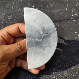 May include: A half-circle shaped piece of gray and white marble with a swirling pattern.